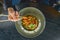 Beautiful young woman eating chinese food called Wok with chopsticks. Wok with meat and fried asparagus in a plate