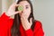 Beautiful young woman eating half fresh green kiwi cover mouth with hand shocked with shame for mistake, expression of fear,