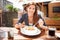 Beautiful young woman eating lasagne in restaurant