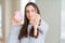 Beautiful young woman eating sugar marshmallow pink donut with angry face, negative sign showing dislike with thumbs down,
