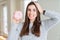 Beautiful young woman eating sugar marshmallow pink donut stressed with hand on head, shocked with shame and surprise face, angry