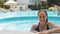 Beautiful young woman emerges from the pool and looks at the camera