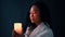 Beautiful young woman enjoy burning candle in her hands in darkness