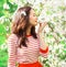 Beautiful young woman enjoying smell spring flowers in garden