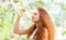 Beautiful young woman enjoys smell spring flowers over garden