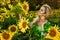 Beautiful young woman in a field of sunflowers. Happy female model is holding sunflower in Sunflowers field. Natural beauty