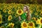 Beautiful young woman in a field of sunflowers. Happy female model is holding sunflower in Sunflowers field. Natural beauty