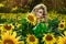 Beautiful young woman in a field of sunflowers. Happy female model is holding sunflower in Sunflowers field. Natural beauty