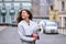 Beautiful young woman with flowers bouquet at city street. Spring portrait of pretty female