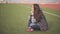 Beautiful young woman on the football field. Girl sitting on the green grass on the playground