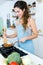 Beautiful young woman frying vegetables into the pan.