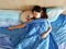 Beautiful young woman or girl cuddles and hugs her best friend pug puppy dog, sleep together under blankets in hipster designer