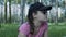 A beautiful young woman in glasses and a cap arranged a lunch in the park among the trees in the green grass.