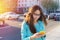 Beautiful young woman in glasses with a smartphone writing