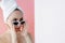 Beautiful young woman in glasses with a towel on her head after bath on pink background