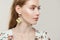Beautiful young woman with golden earrings on white, profile