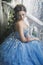 Beautiful young woman in gorgeous blue long dress like Cinderella with perfect make-up and hair style