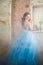 Beautiful young woman in gorgeous blue long dress like Cinderella with perfect make-up and hair style