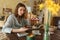 Beautiful young woman is guessing on cards with tarot, runes on wooden table and uses an online app in phone to