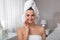 Beautiful young woman with hair wrapped in towel cleaning her face at home