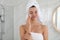 Beautiful young woman with hair wrapped in towel cleaning her face indoors