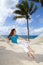 Beautiful young woman in a hammock on the beach on background of palm trees and the sea