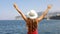 Beautiful young woman with hat and raised arms looking at stunning panoramic village of Sorrento on Sorrentine Peninsula, Italy