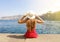 Beautiful young woman with hat sitting on the edge looking at stunning panoramic village of Sorrento on Sorrentine Peninsula,