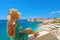 Beautiful young woman with hat sitting on wall looking at stunning panoramic village of Dubrovnik in Croatia, Europe