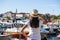 Beautiful young woman in hat standing close to the boats at Mediterranean city