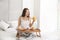 Beautiful young woman having breakfast on bed at home