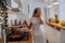 Beautiful young woman in headphones listening to music in kitchen. Frying pancakes.