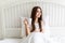 Beautiful young woman at her bedroom drinking tea in the morning.