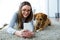 Beautiful young woman with her dog using mobile phone at home.