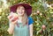 Beautiful young woman holding an apple on a farm. Happy lady picking apples in an orchard. Fresh fruit produce growing