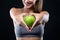 Beautiful young woman holding an apple over black background.