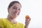 A beautiful young woman holding an apricot while smiling at the camera . Healthy food concept