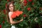 Beautiful young woman holding bouquet on red roses near wall rose background