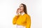 Beautiful young woman holding hand near her open mouth, tells gossip in secret. Studio shot, white background