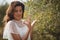 Beautiful young woman holding olive by tree at farm