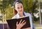 Beautiful young woman holding open book and reading on bench