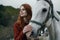 Beautiful young woman holding a white horse, portrait, mountains, nature