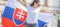 Beautiful young woman holds a flag of Slovakia oudoors on a sunny day, wearing sunglasses