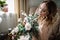 Beautiful young woman in a house dress in the boudoir, decorated with beautiful flowers, sitting on a white bed with a canopy, fas