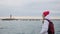 Beautiful young woman in jacket with backpack walk on pier at harbor. Attractive female tourist is visiting port