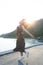 Beautiful young woman jumping at sea side against sun lighting over sky