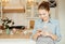 A beautiful young woman in the kitchen holds a smartphone and types a message.