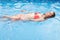 Beautiful young woman learning to swim on the back in the pool