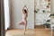 Beautiful young woman in light pink sportswear working out indoors