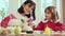 Beautiful young woman and little girl, other and daughter sitting at table at home, preparing for Easter holiday